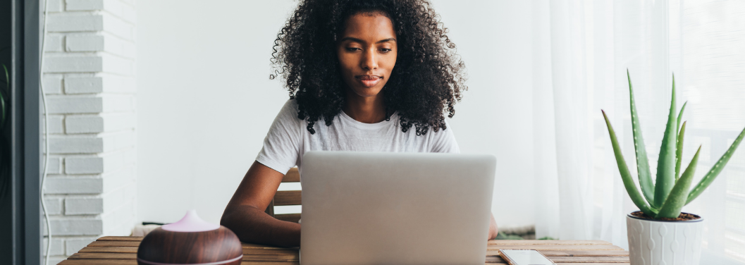 Người phụ nữ da đen ngồi bên chiếc máy tính xách tay đang đăng ký cho con đi học